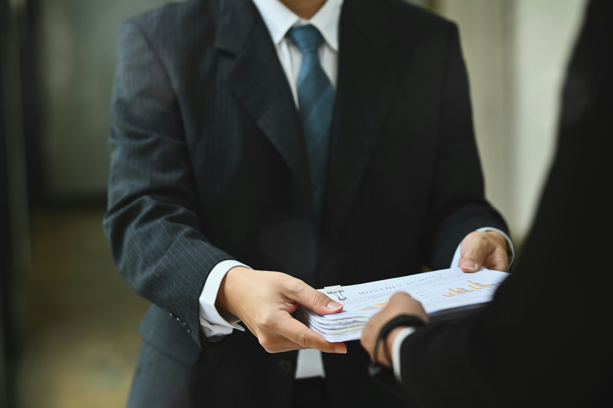 Financial inspector hands handing document to his colleague in office corridor